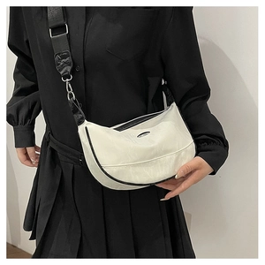 Detail of white half-moon crossbody bag with black wide strap and oval metal logo