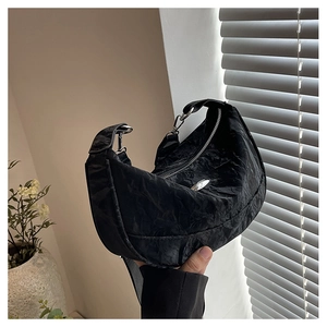 Macro shot of black pleated crescent hobo bag featuring a silver metal logo detail