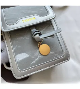 Close-up of grey marble texture crossbody phone bag with gold metal logo and plush pendant
