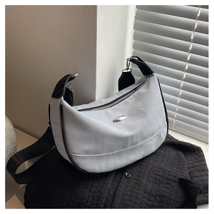 Detail of light blue crescent bag with pleated texture and silver metal buckle accent