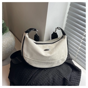 Detail of the white half-moon bag featuring black strap and silver metal buckle