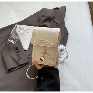 Details der weißen Handy-Umhängetasche mit Fashion-Schriftzug und Plüschanhänger