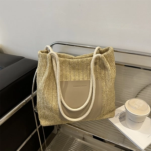 Large woven tote bag with leather pocket and cotton rope handles on a metal rack