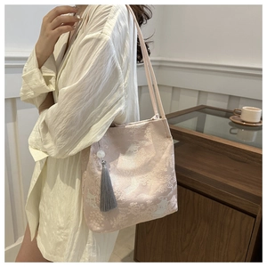 Detailed embroidery on light pink Chinese brocade tote bag with a jade tassel pendant