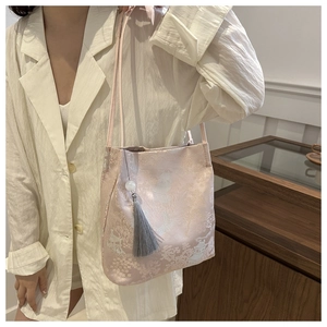Detail of pink satin shoulder bag featuring traditional Chinese embroidery and silk tassel