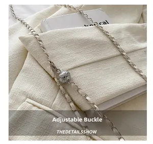 Close-up of adjustable metal ball buckle on leather-interwoven chain shoulder strap