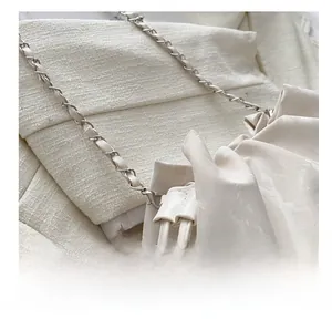 Macro view of beige ruched fabric bucket bag with silver metal chain woven strap detail