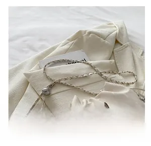 Detail of cream bucket bag featuring silver butterfly charm and chain-leather strap