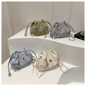 Close-up of drawstring bucket bags in four colors with butterfly charms and metal chains