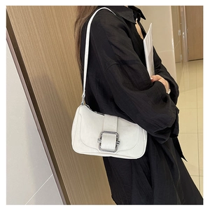 Detailed close-up of white faux leather shoulder bag with a sleek silver rectangular buckle