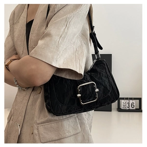 Detail of black pleated shoulder bag with large silver buckle on a stylish model