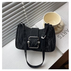 Detail of black pleated shoulder bag featuring a large silver square metal buckle and strap