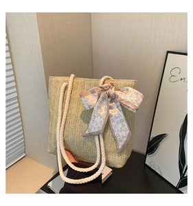 Detail of hand-woven straw tote bag with heart print silk scarf and rope handles