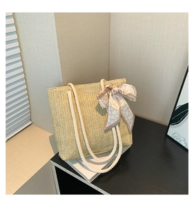 Detail of beige woven straw tote bag with cotton rope handles and heart print silk scarf