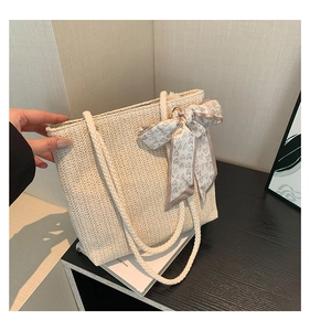 Detail of herringbone weave straw tote bag with rope handle and heart pattern scarf