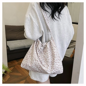 Gros plan du motif floral rouge sur le sac à bandoulière en toile avec cordon blanc