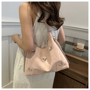 Pink hobo bag with silver butterfly charms shown in a lifestyle setting with a white dress