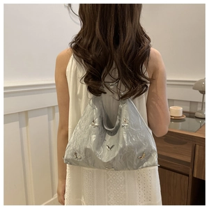 Achteraanzicht van zilveren hobo-tas met vlinderbedels en geplooide textuur op model