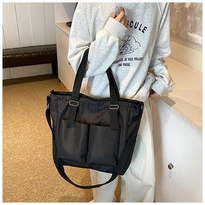 Detail of black waterproof nylon tote bag with two front pockets and adjustable strap
