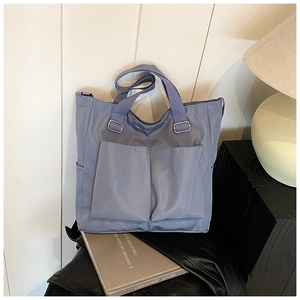 Detail of blue large capacity tote bag featuring dual front square pockets and nylon texture