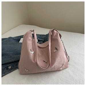 Detail van de roze tas met zilveren vlinderbedeltjes en een stijlvolle metalen ketting