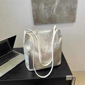 Elegant Chinese embroidery tote bag with floral patterns and a jade tassel on desk