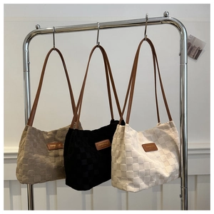 Detail of checkered nylon tote bags in three colors hanging on a minimal display stand