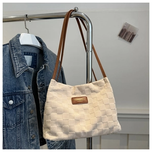 Close-up of white checkered tote bag with brown leather tag and slim shoulder strap