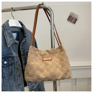 Detail of beige tote bag featuring textured checkerboard pattern and brown leather straps