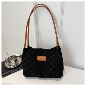 Detail of black checkered velvet tote bag with brown leather logo and slim handles