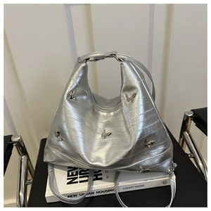Detail of silver tote bag with metallic butterfly accents and pleated texture finish