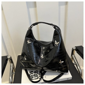 Detail of black glossy tote bag with silver butterfly metal ornaments and hobo style