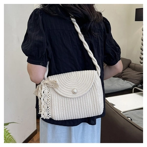 Detail of white woven crossbody bag featuring a large pearl button and lace bow accent