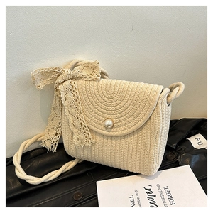 Detail of cream woven lace crossbody bag with pearl buckle and bow on black leather