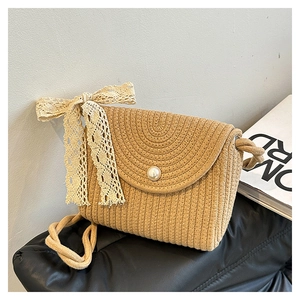 Detailed texture of beige woven shoulder bag featuring lace bow and pearl button detail
