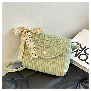 Detail of light green woven crossbody bag featuring a pearl clasp and lace bow detail