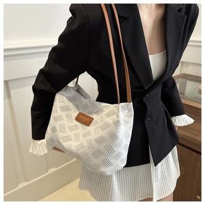 Close-up of white woven tote bag with brown leather straps and fashion label detail