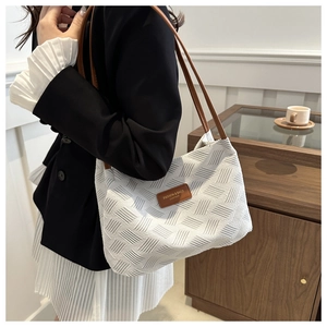 Detail of white woven texture shoulder bag with premium brown leather handles and logo
