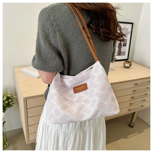 Detail showing the woven geometric pattern and brown leather straps of the tote bag