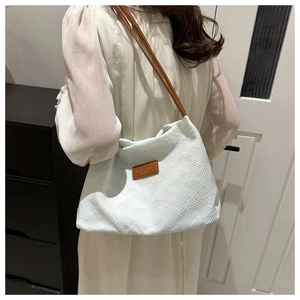 Detail view of light green pleated shoulder bag with brown leather strap on model