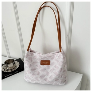 Detail of lavender woven tote bag with brown leather handles and brand logo patch