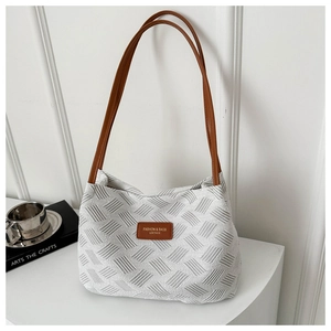 Detail of white woven tote bag featuring geometric texture and brown leather strap