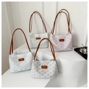 Close-up of woven shoulder bags in blue, green, pink and grey with leather handles