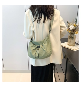 Close-up of light green crossbody bag with pleated nylon fabric and adjustable wide strap