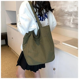 Detail of olive green nylon tote bag showing side pocket and spacious design