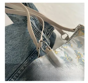 Close-up of silver metal ring connecting the off-white strap and butterfly embroidered bag