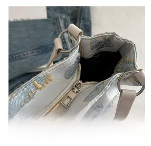 Close-up of smooth silver metal zipper and exquisite gold floral embroidery on light blue bag