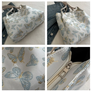 Detail of white butterfly jacquard tote bag featuring premium fabric and silver metal zipper