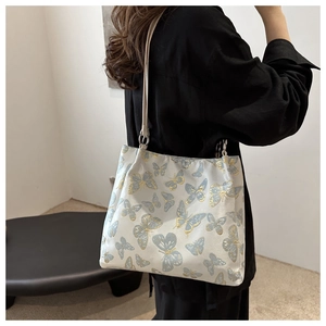 Detail of elegant shoulder tote bag with blue and gold embroidered butterfly patterns