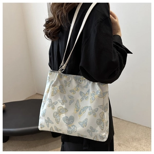 Detail of white bucket bag with blue butterfly jacquard pattern on a shoulder strap
